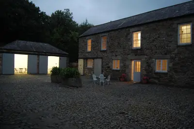 a stone building with two chairs in front of it at Stable House in Redruth