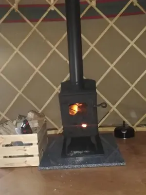 a stove in a room with a wooden box at Looe Yurts in Looe