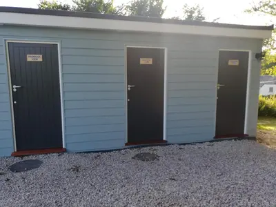 a row of three doors on a building with gravel at Looe Yurts in Looe