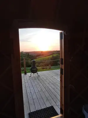 an open door to a deck with the sunset at Looe Yurts in Looe