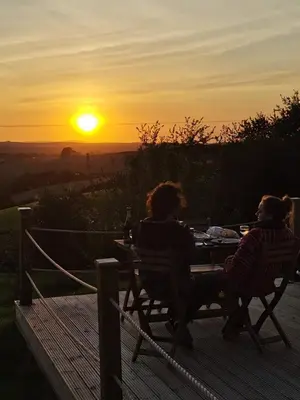 two people sitting at a table watching the sunset at Looe Yurts in Looe