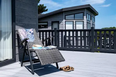 a wicker chair on a porch with a house at Edge of Padstow, 2 bedroom luxury lodge in Padstow