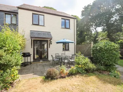 a house with a patio with a table and an umbrella at Robinswood in Falmouth