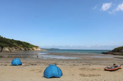 two tents on a sandy beach next to the ocean at Robinswood in Falmouth