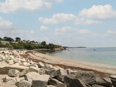 a beach with rocks and people on the water at Robinswood in Falmouth
