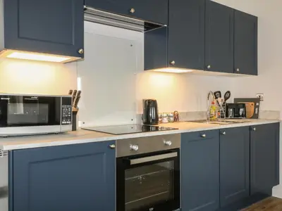 a kitchen with navy blue cabinets and a microwave at Primrose End in Bude