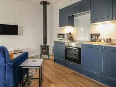 a kitchen with blue cabinets and a blue couch and a stove at Primrose End in Bude