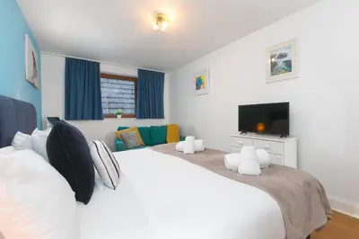 a bedroom with a large white bed and a tv at 11 Carrack Widden in St Ives