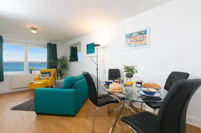 a living room with a table and a blue couch at 11 Carrack Widden in St Ives