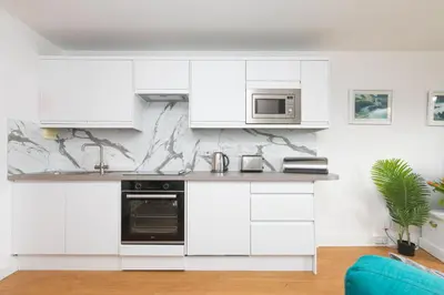 a white kitchen with white cabinets and a microwave at 11 Carrack Widden in St Ives