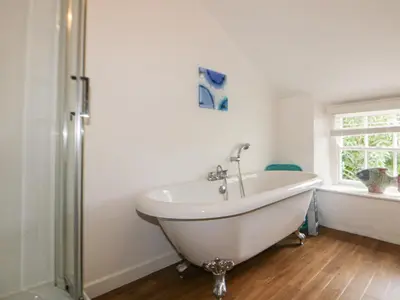 a white bath tub in a bathroom with a window at Great Western Farmhouse in Newquay