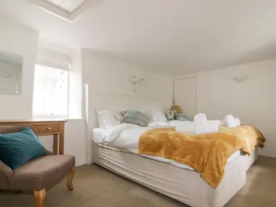 a bedroom with a large bed and a chair at Great Western Farmhouse in Newquay