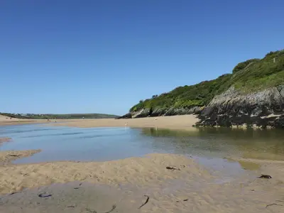 a beach with a body of water next to a cliff at Great Western Farmhouse in Newquay