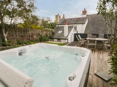 a hot tub on the deck of a house at Great Western Farmhouse in Newquay