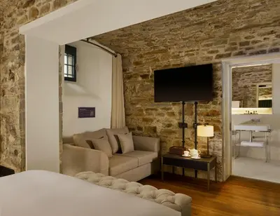 a living room with a couch and a tv on a brick wall at Bodmin Jail Hotel in Bodmin