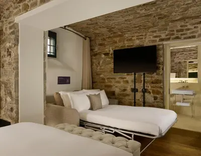 a bedroom with two beds and a tv on a brick wall at Bodmin Jail Hotel in Bodmin