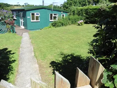 a garden with a blue house in the background at Rostowan Villa, very near the Beach in Truro