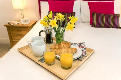 a tray of breakfast food on a bed with flowers at Apartment by the beach, sea views in St Merryn