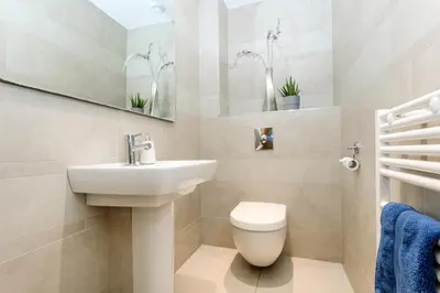 a bathroom with a sink and a toilet and a mirror at Apartment by the beach, sea views in St Merryn