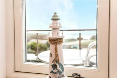 a lighthouse figurine sitting on a window sill at Apartment by the beach, sea views in St Merryn