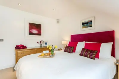 a bedroom with a large white bed with a red headboard at Apartment by the beach, sea views in St Merryn