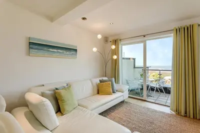a living room with a white couch and a large window at Apartment by the beach, sea views in St Merryn
