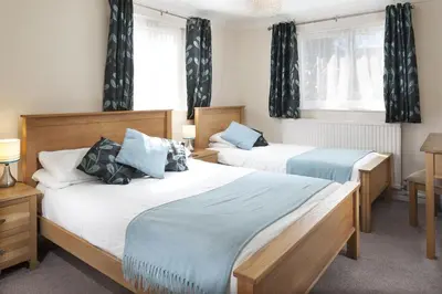 two beds in a room with windows and curtains at Gwithian Holidays in Hayle