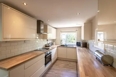 a large kitchen with white cabinets and wooden floors at Gwithian Holidays in Hayle