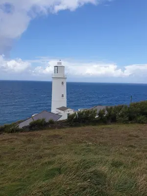 a white lighthouse on the edge of the ocean at Detached Bungalow in North Cornwall in Bodmin