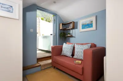 a living room with a red couch and a window at Navas Nook in Falmouth