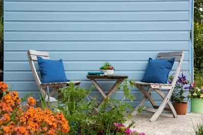 two chairs and a table in front of a blue wall at Navas Nook in Falmouth