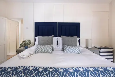 a large bed with a blue headboard and pillows on it at Navas Nook in Falmouth