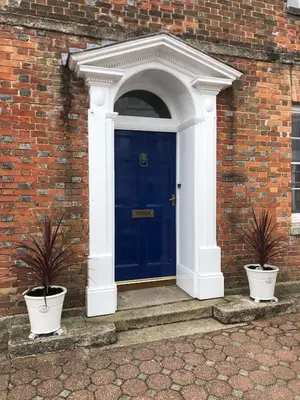 a blue door in a brick building with two potted plants at Bank Place in Falmouth