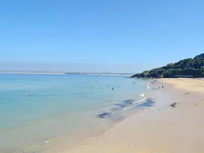 a beach with a bunch of people in the water at The Cottage in St Ives
