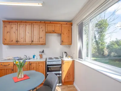 a kitchen with wooden cabinets and a table and a window at 117 Atlantic Reach-Uk32918 in Saint Columb Major