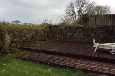 a wooden deck with a bench and a fence at Okewoon Farm in Lanivet