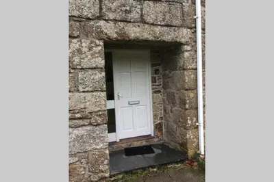 a white door in a stone wall with a black doorstep at Okewoon Farm in Lanivet