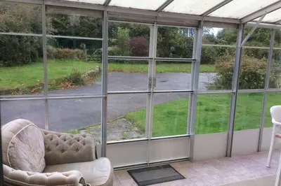 a room with large glass windows and a chair at Okewoon Farm in Lanivet