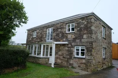 an old stone house with a white door at Okewoon Barn in Lanivet