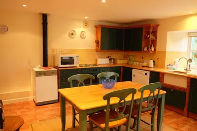 a kitchen with a wooden table and chairs and a table and a kitchen with at Okewoon Barn in Lanivet