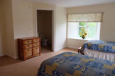 a bedroom with two beds and a window and a dresser at Okewoon Barn in Lanivet