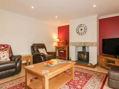 a living room with couches and a table and a fireplace at Meadowside in Truro