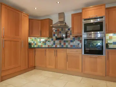 a kitchen with wooden cabinets and a microwave at Meadowside in Truro