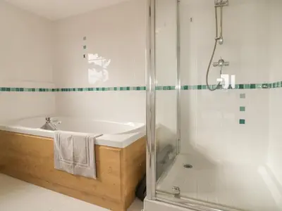 a white bathroom with a tub and a shower at Meadowside in Truro