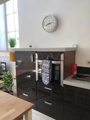 a kitchen with a clock on the wall above a stove at The Old English Rooms in Falmouth