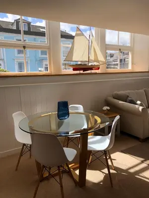 a living room with a glass table and a sailboat on the wall at The Old English Rooms in Falmouth
