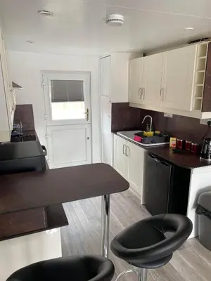 a kitchen with white cabinets and a table and chairs at 43 annexe in Newquay