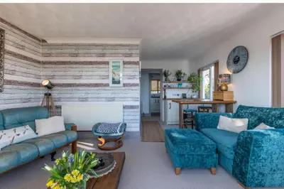 a living room with blue couches and a kitchen at 1 Bed Flat - Sleeps 2 - Pets - Balcony - Parking in Looe
