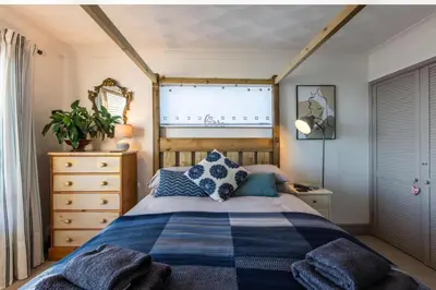 a bedroom with a bed with blue pillows and a window at 1 Bed Flat - Sleeps 2 - Pets - Balcony - Parking in Looe