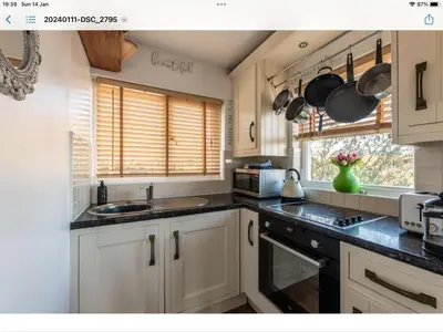 a kitchen with white cabinets and a sink and a microwave at 1 Bed Flat - Sleeps 2 - Pets - Balcony - Parking in Looe